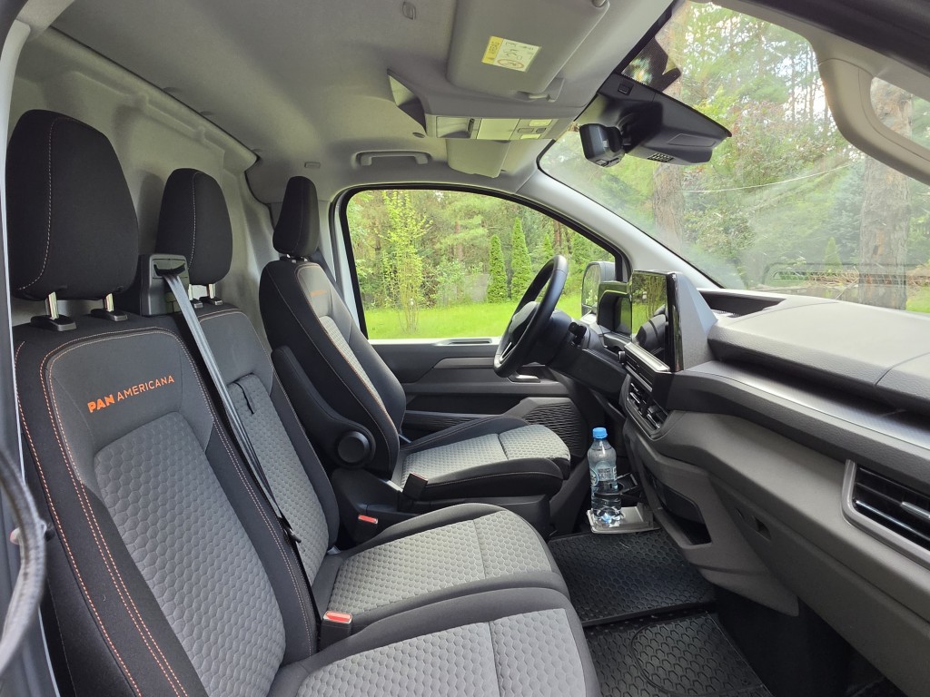 Dwuosobowa kanapa pasażerów z rozłożonym stolikiem w kabinie Volkswagen Transporter T7